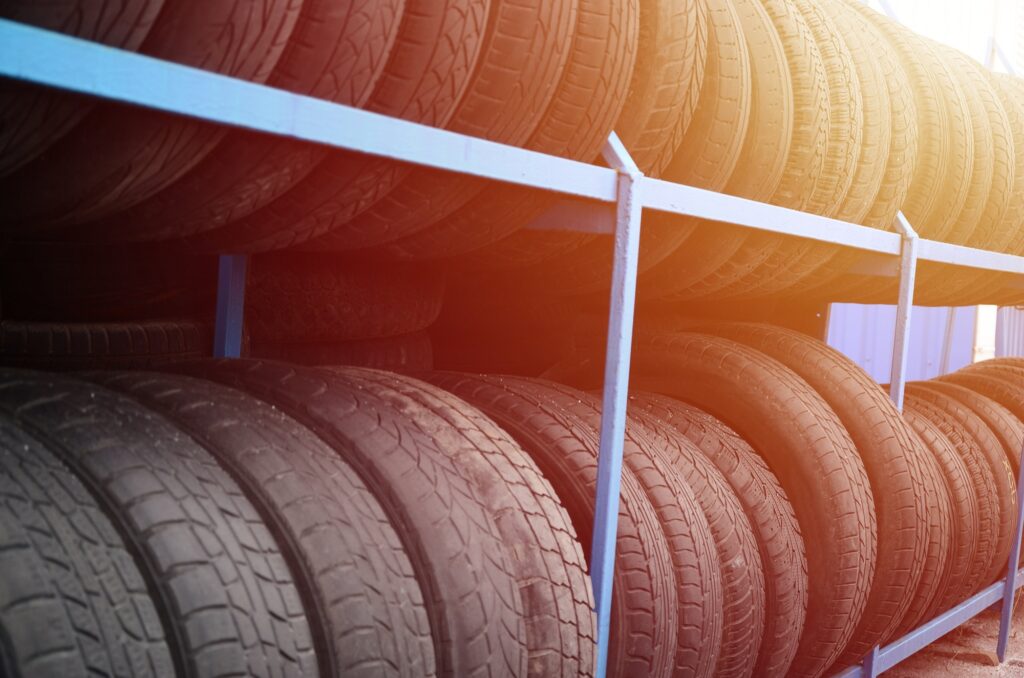 Rack with variety of car tires in automobile store. Many black tires. Tire stack background